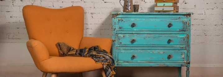 Orangefarbener Sessel und blaue Kommode